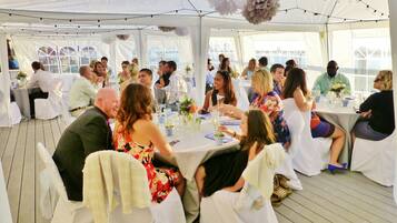 Un espacio para eventos con carpas, mesas dispuestas para invitados, manteles blancos y centros de mesa florales.