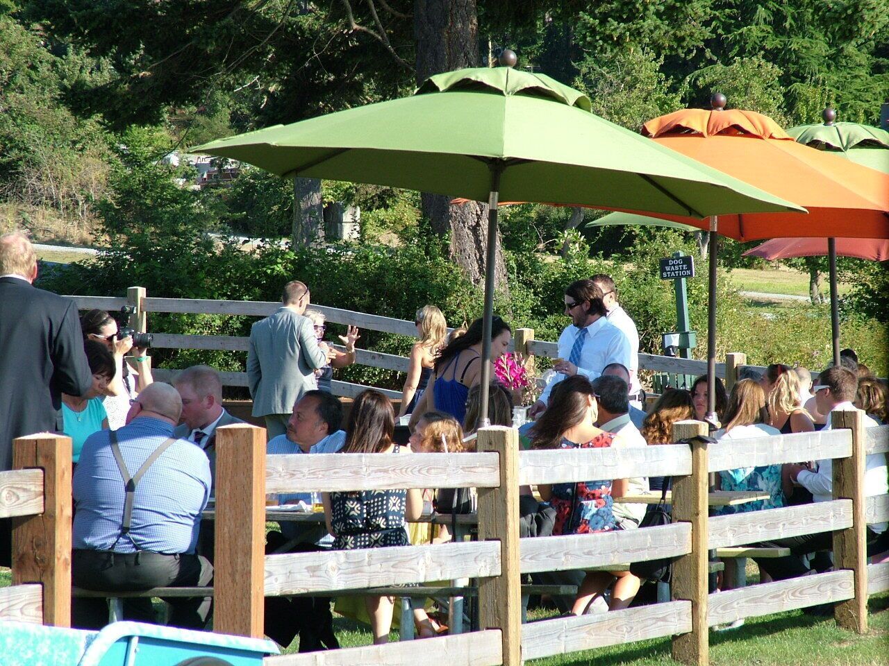 A group of people seated at tables under umbrellas in an outdoor setting.