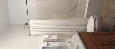 A modern bathroom with a glass shower enclosure, a wooden vanity with a marble countertop, and neatly arranged towels.