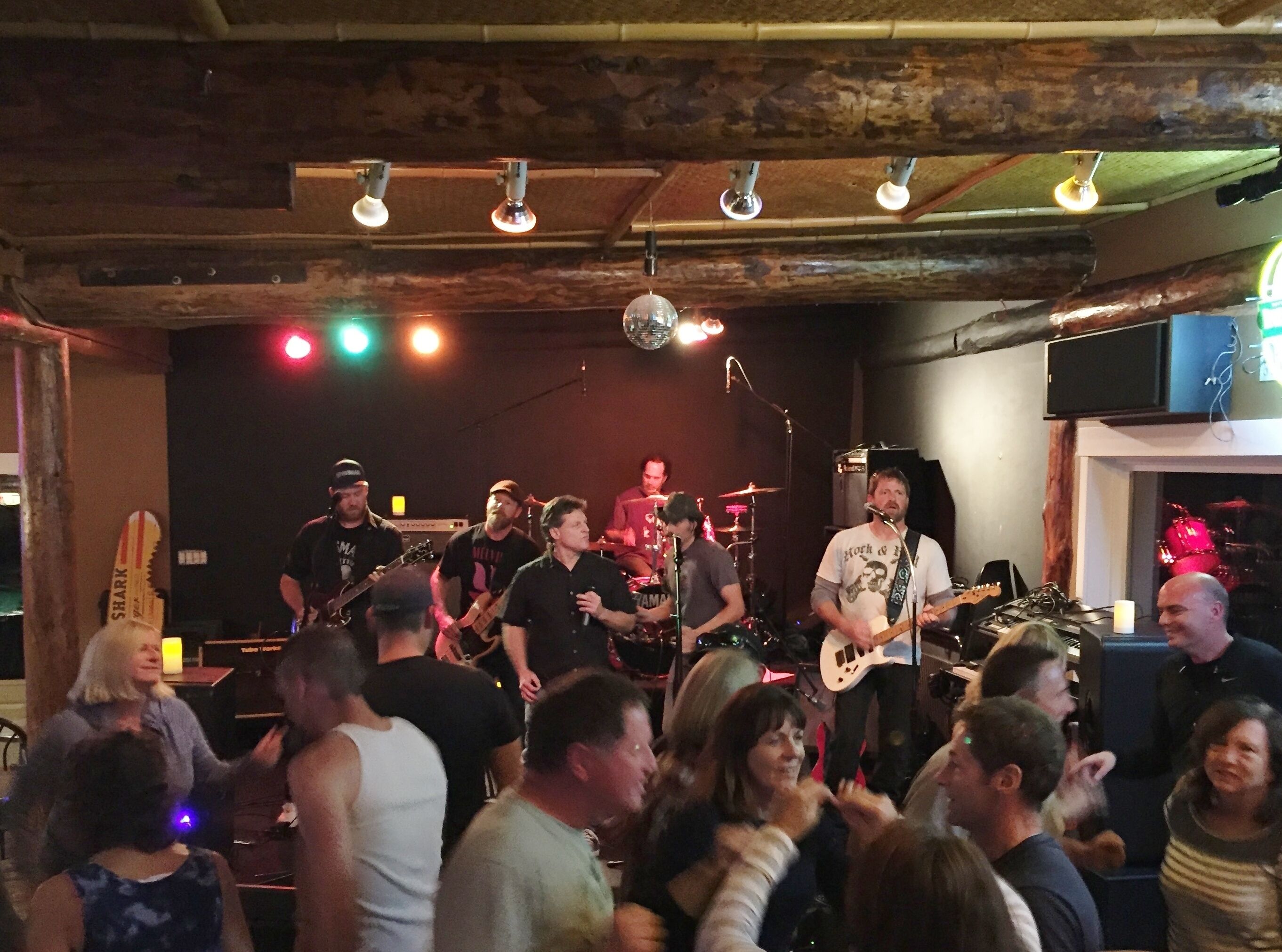 Una banda tocando en un escenario, con una multitud en primer plano.