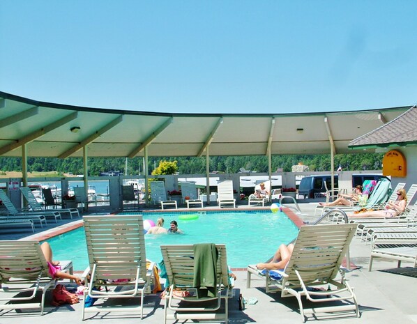 A pool area with lounge chairs and a covered section.