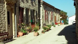A narrow street lined with stone buildings, some with balconies and potted plants. - 13th Century Townhome (Monflanquin)