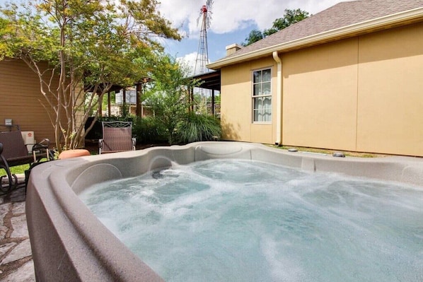Un jacuzzi en un patio trasero con una casa al fondo.