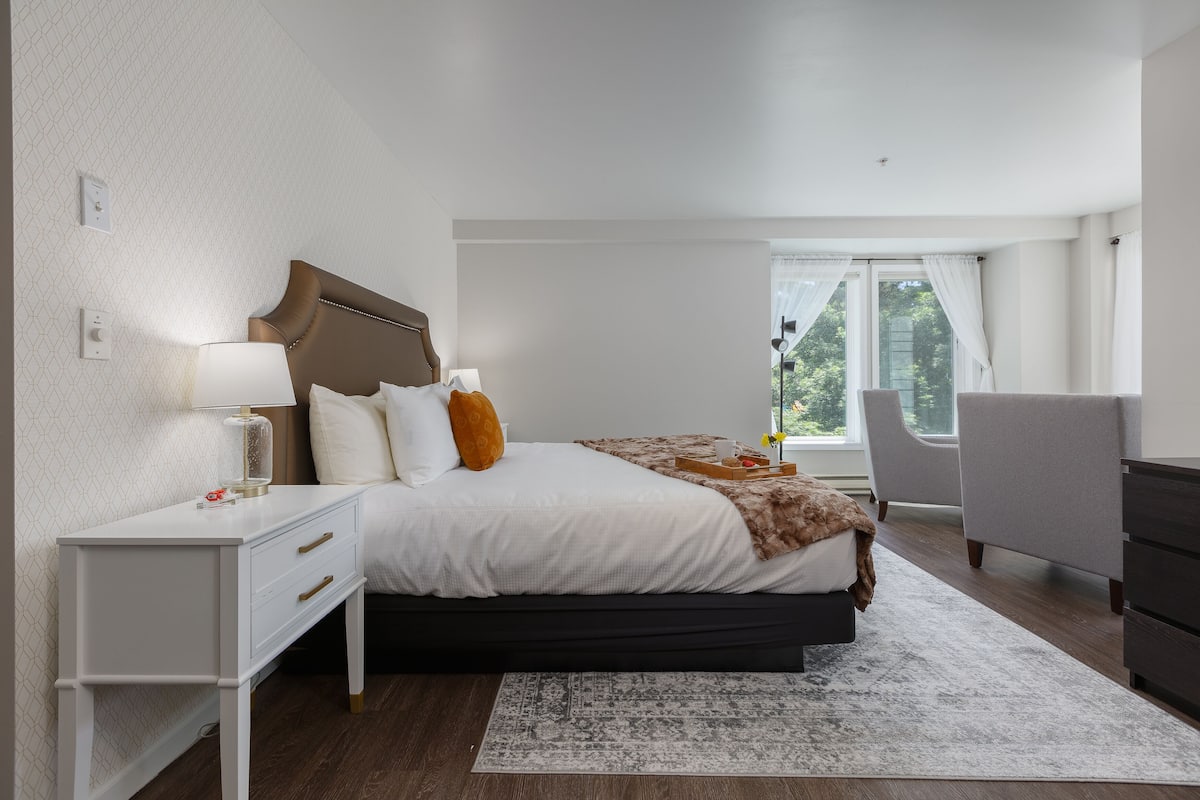 A modern bedroom with a large bed, bedside tables, a desk, and a chair.
