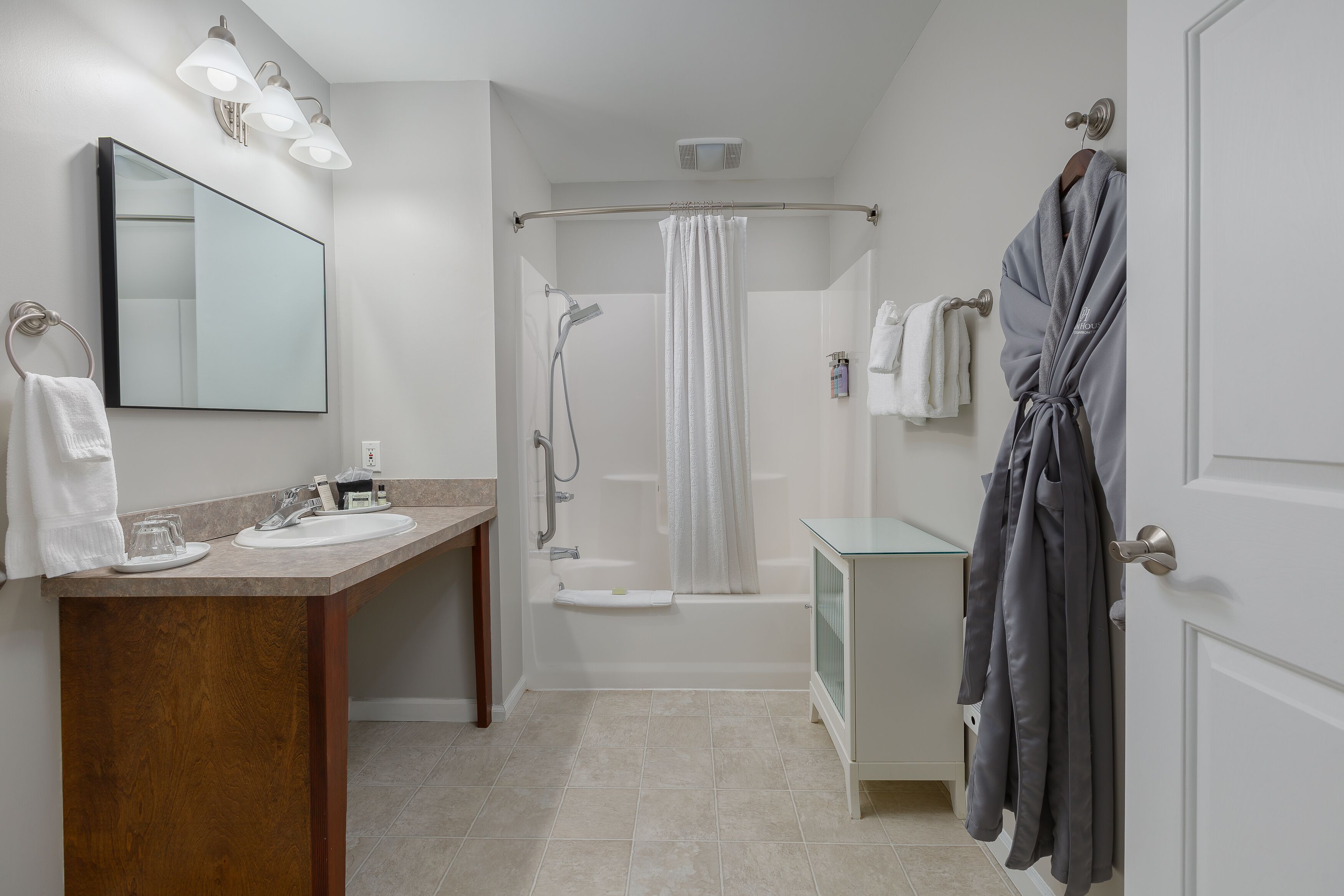 Un bagno moderno con un mobile bagno in legno, uno specchio grande, una vasca e una doccia.