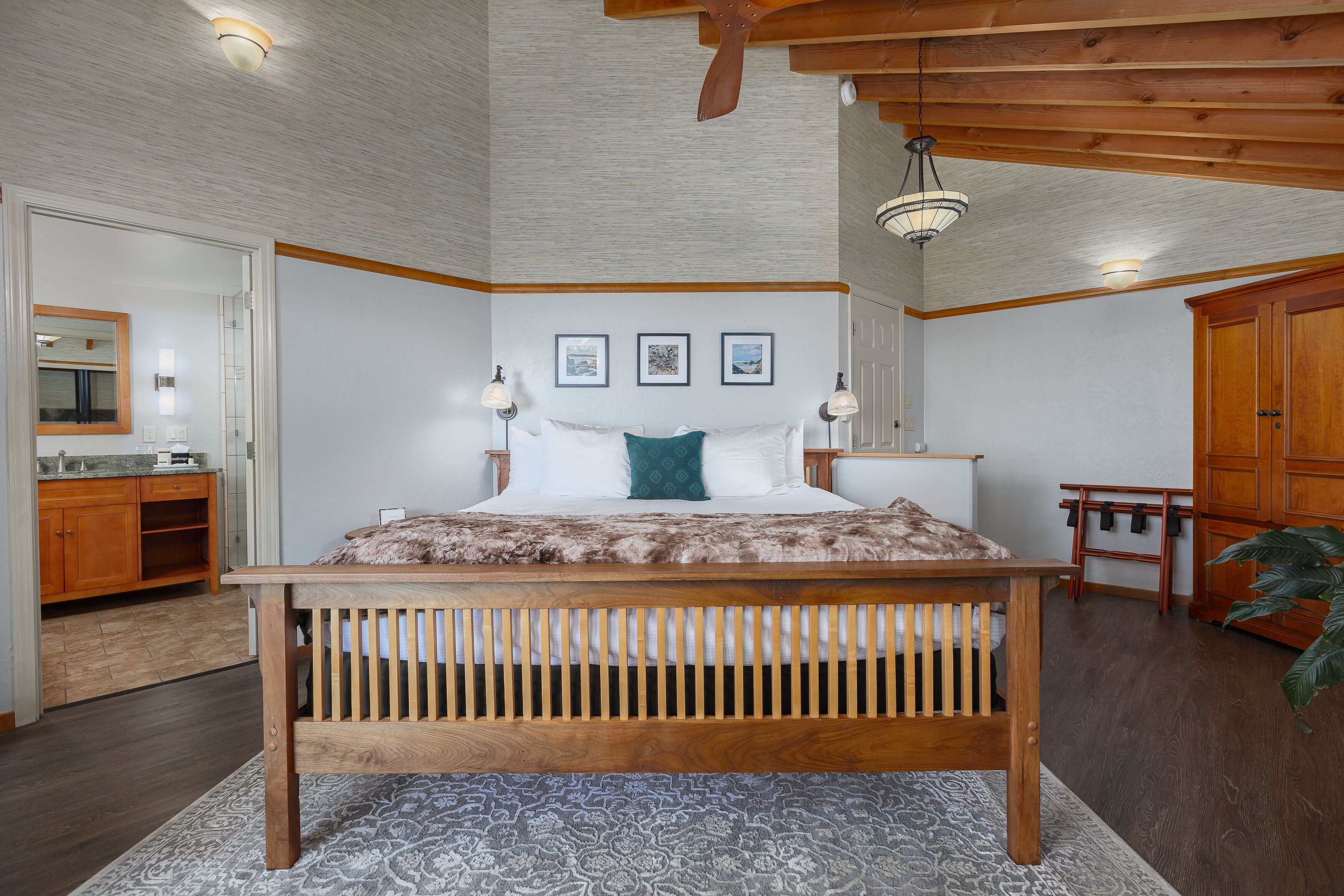 Un dormitorio con una cama de madera, una mesita de noche, un aparador y un ventanal grande.