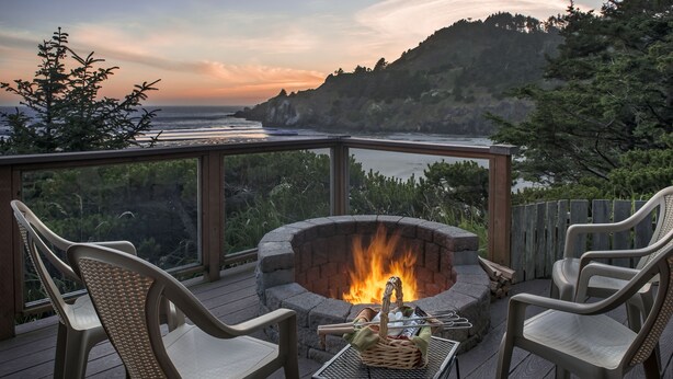 A deck with a fire pit, chairs, and a table with a basket. - Ocean House (Newport)
