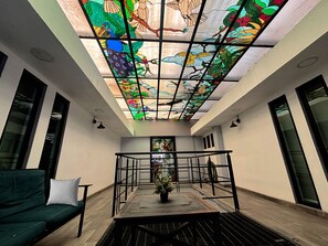 Un intérieur moderne avec un plafond en verre, un escalier et un canapé vert.