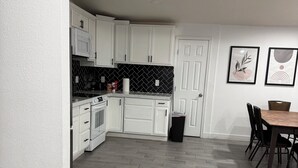 Una cocina moderna con armarios blancos, salpicadero blanco y negro, y piso con patrón de espiga.