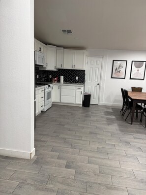 A modern kitchen with white cabinets, a black and white backsplash, and a herringbone-patterned floor.