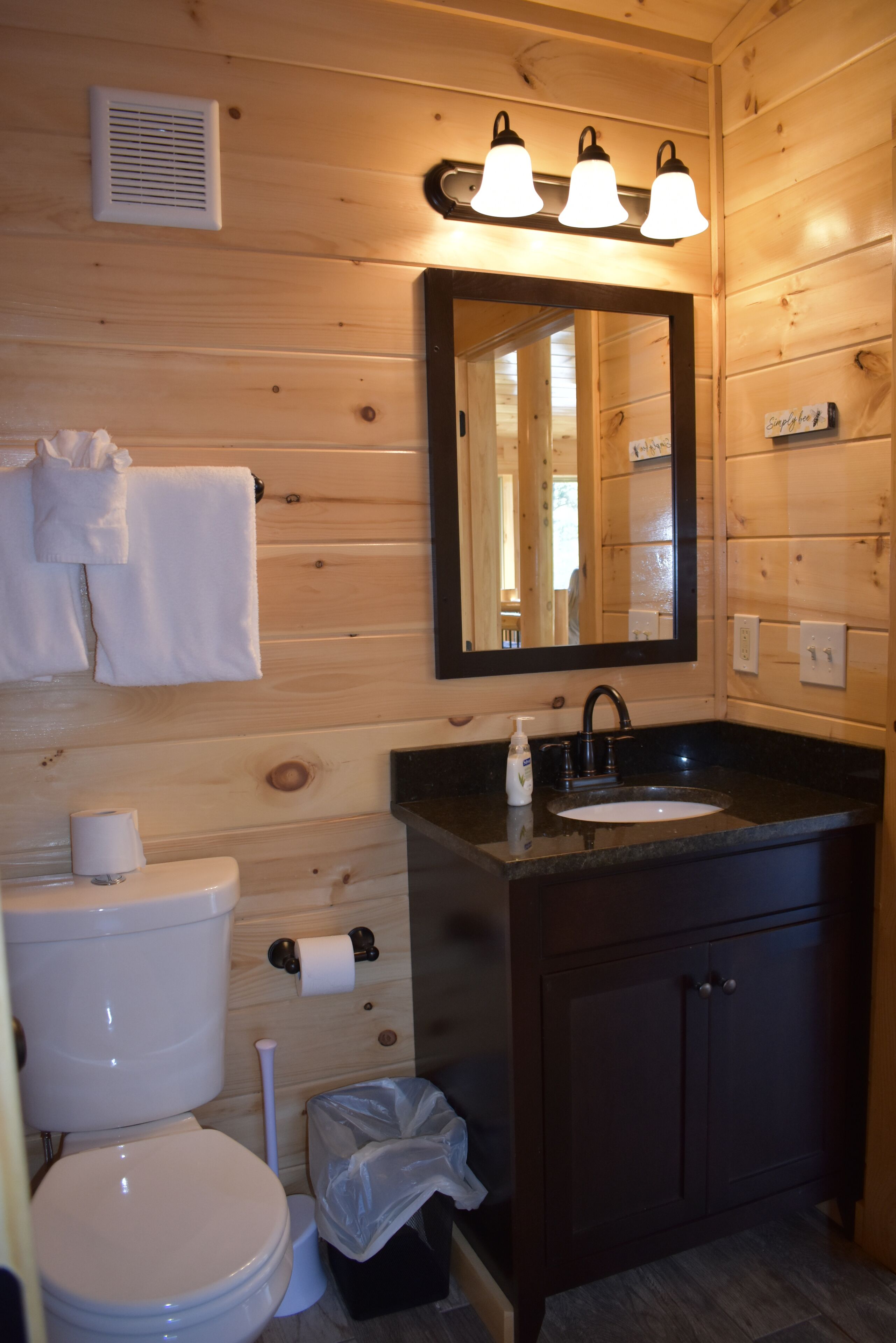 Een betegelde badkamer met toilet, wastafel, spiegel en handdoekhouder.