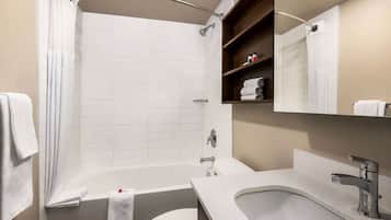 A modern bathroom with a bathtub, toilet, and sink. There are towels and toiletries visible.