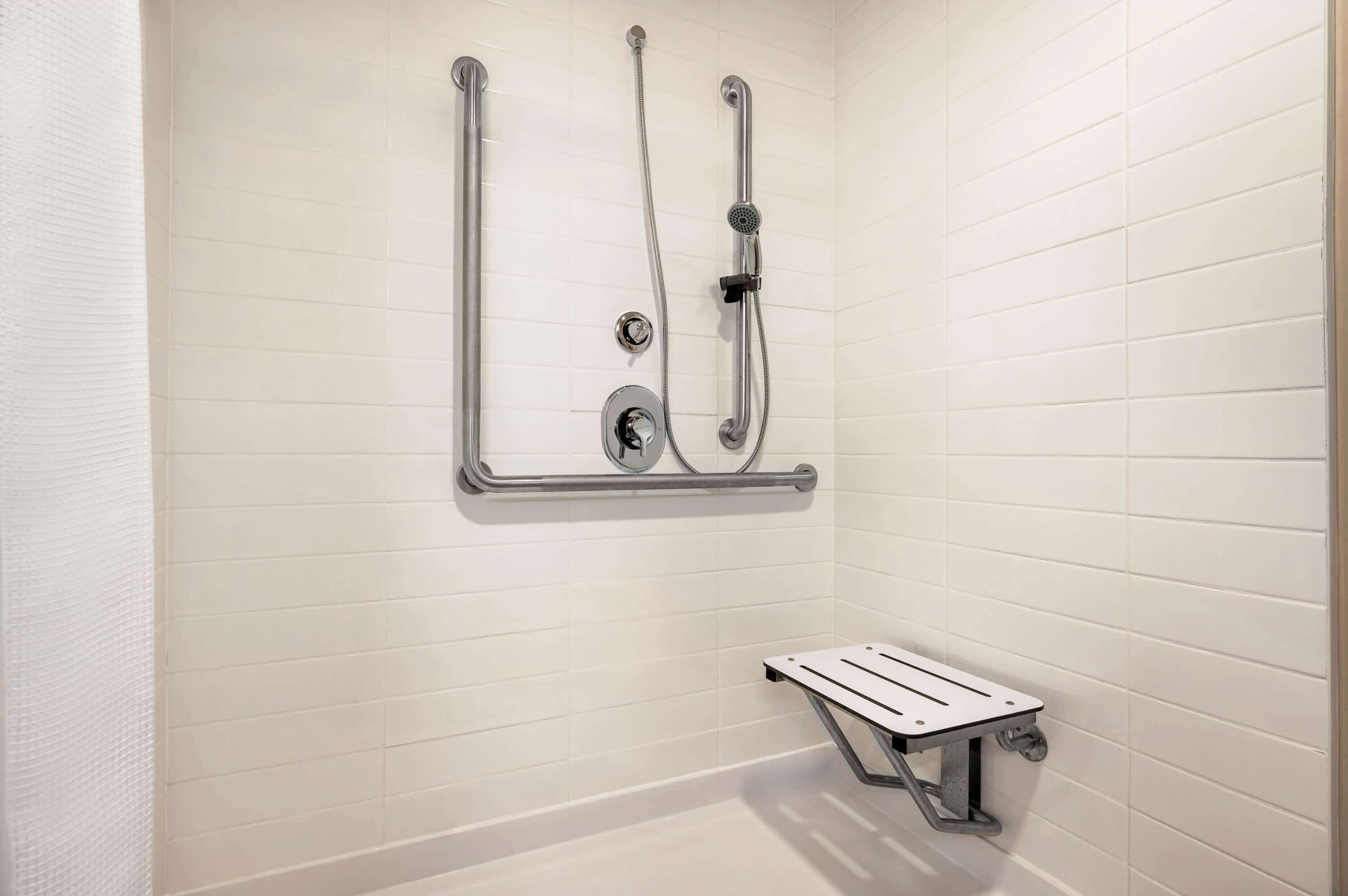 Une douche équipée d’un pommeau de douche à main, d’un pommeau de douche fixe et d’un siège de douche à main.