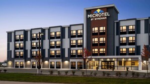 Un microhotel moderno con un letrero llamativo, varios pisos y una entrada bien iluminada.