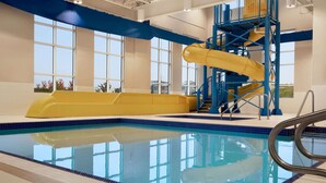 Una piscina interior con un tobogán amarillo y barandillas azules.