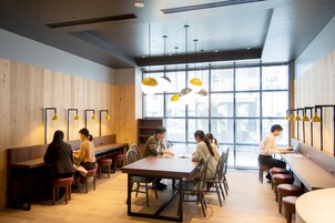 A modern dining area with wooden walls, multiple seating options including tables and benches, and pendant lighting.