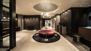 Un vestíbulo moderno con una zona de estar circular, un mostrador de recepción y una pared de ladrillo.