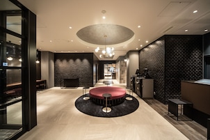 A modern lobby with a circular seating area, a reception desk, and a brick wall.