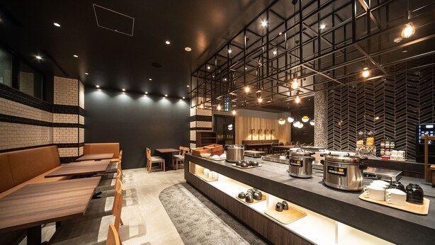 Un restaurante moderno con una barra larga, zona de estar y cocina visible.