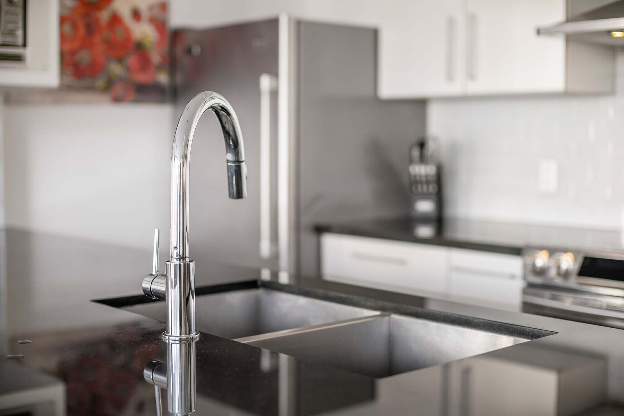 Una cocina moderna con un lavamanos de acero inoxidable, un grifo y una cafetera.