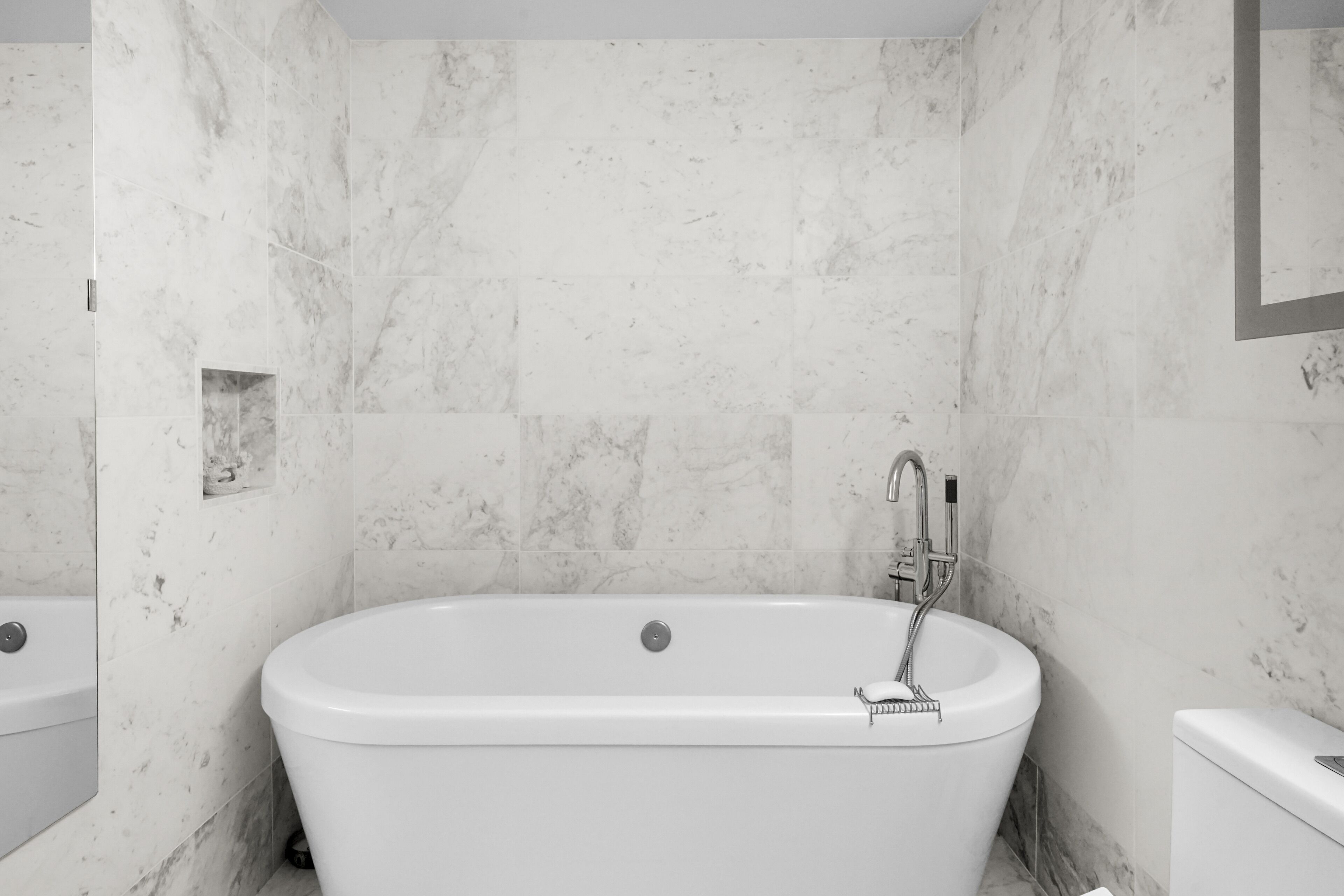 A modern bathroom with a freestanding bathtub, a built-in shower, and a toilet.