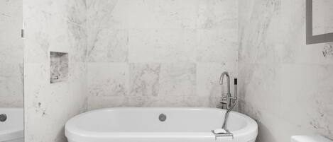 A modern bathroom with a freestanding bathtub, a built-in shower, and a toilet.
