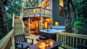 A wooden deck with outdoor seating, a hot tub, and a staircase leading to a balcony. - Newly Rebuilt Home - Hot Tub - Sauna - Sleeps 14 (Wintergreen Resort)