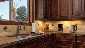 A kitchen with wooden cabinets, a granite countertop, a stainless steel sink, and a window with a view of trees. - Zion (East) Luxurious Home King Beds WiFi Privacy Hot Tub (Orderville)