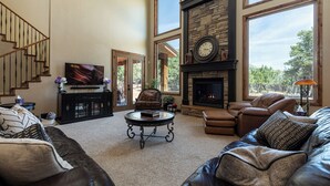 A spacious living room with a fireplace, leather sofas, a coffee table, and a staircase. - Zion (East) Luxurious Home King Beds WiFi Privacy Hot Tub (Orderville)
