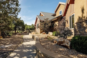 Stunning home with a gabled roof, surrounded by a beautifully landscaped garden and a pathway leading to the entrance.