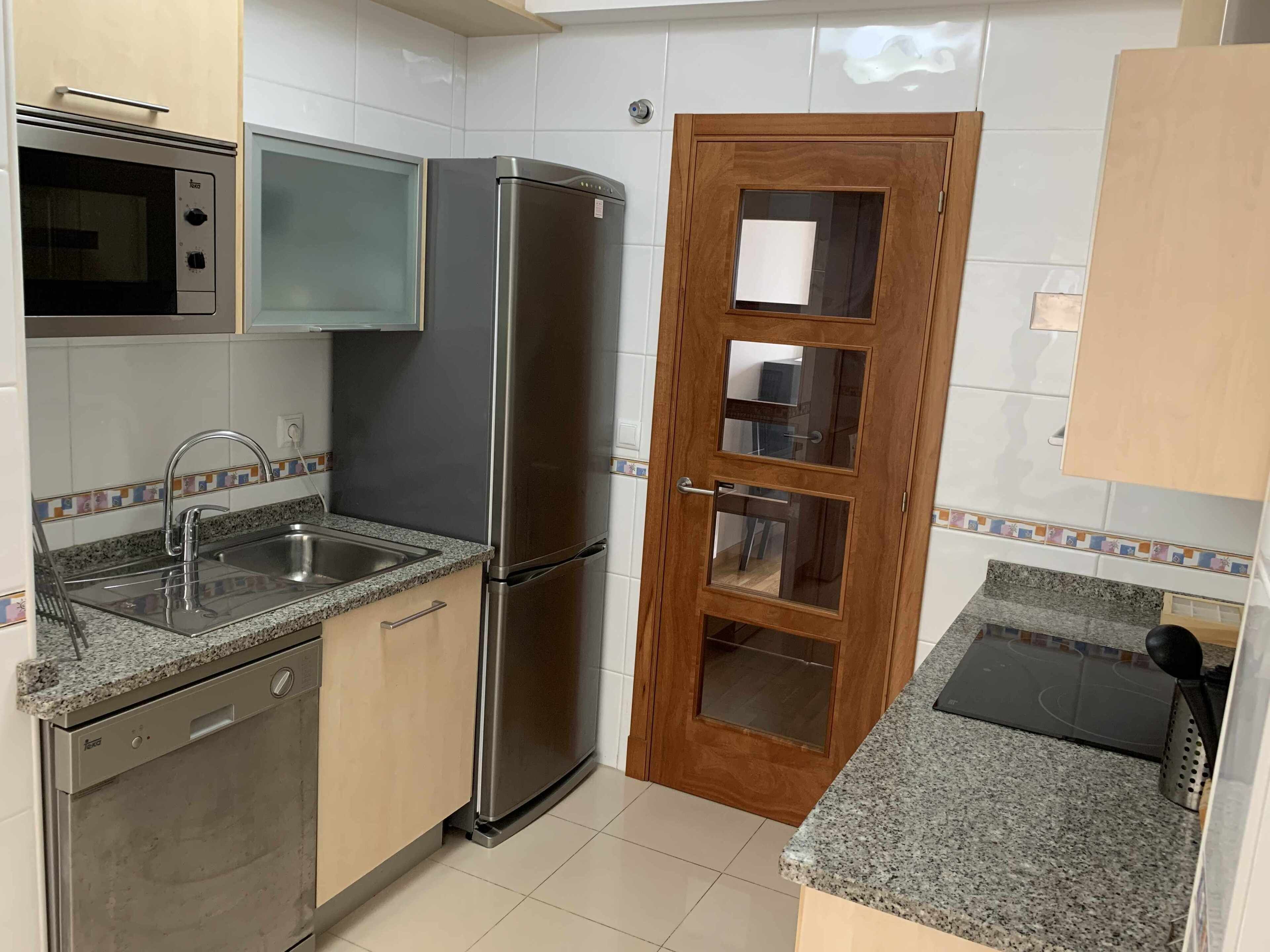 Eine Küche mit Edelstahlkühlschrank, Mikrowelle, Spüle und Holzausstattung.
