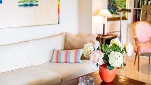 A cozy living room with a sofa, a colorful striped pillow, a vase with flowers, a wooden table, and a lamp. - LE CHATEAU DE LA PINEDE AP4198 (Juan-les-Pins)