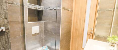 Une salle de bain avec douche, toilettes et lavabo.