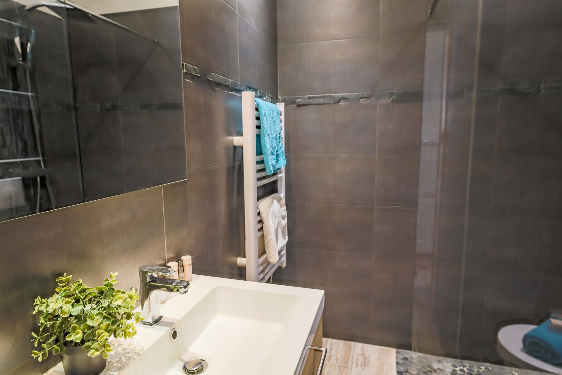 A modern bathroom with a large white sink, a mirror, and a shower area.