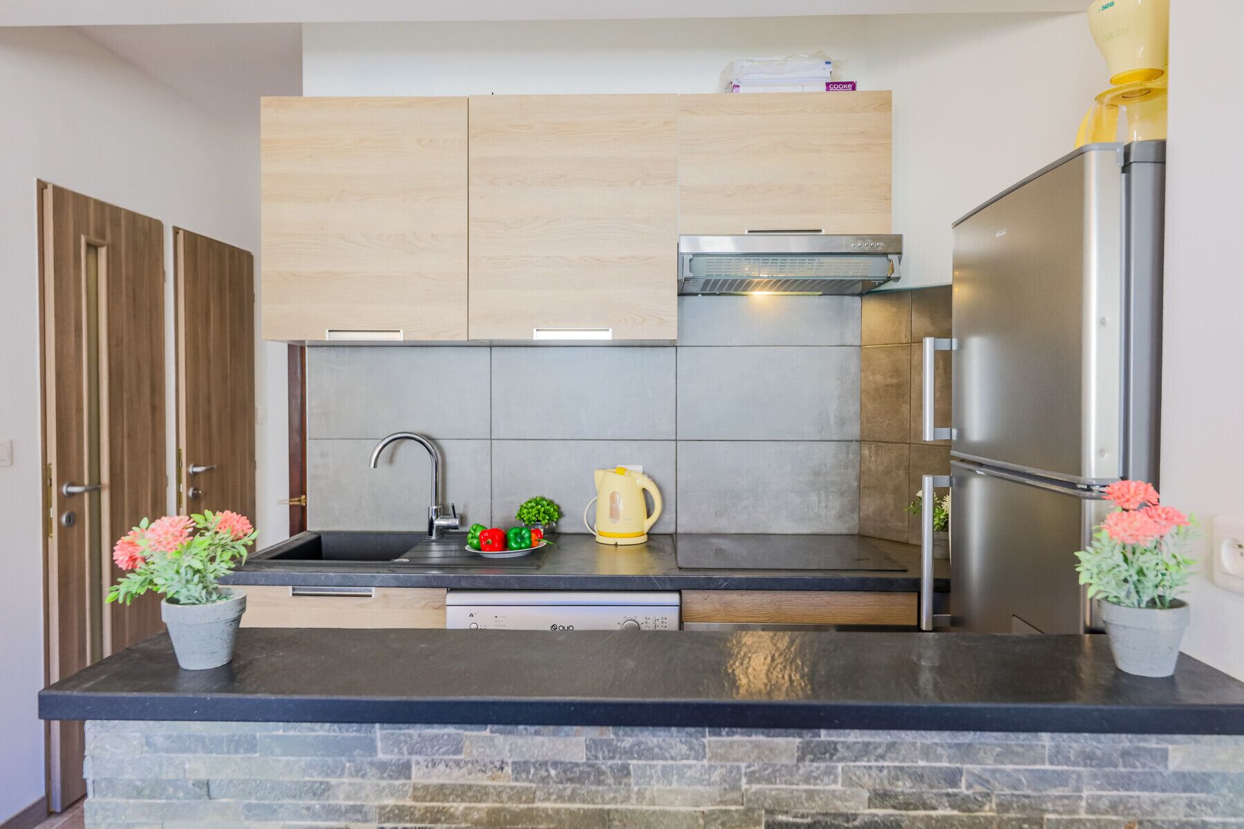 Una cocina moderna con encimera negra, electrodomésticos de acero inoxidable y armarios de madera.