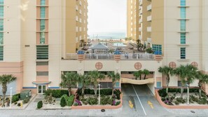 Un hôtel à plusieurs étages doté d’une cour intérieure, de palmiers et d’un espace piscine.