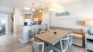 Une cuisine moderne avec un îlot central, une table à manger en bois et des chaises blanches.
