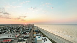 A coastal cityscape with a beach, buildings, and a pier.