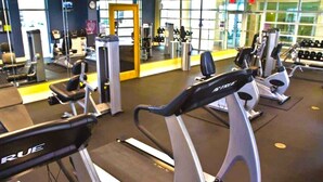 Un gimnasio con cintas de correr, máquinas de pesas y mancuernas.