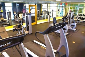 Un gimnasio con cintas de correr, máquinas de pesas y mancuernas.