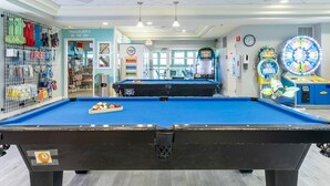 Una mesa de billar con superficie de fieltro azul, un espacio de premios y una zona de juegos infantiles con un carrusel.