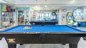 A pool table with a blue felt surface, a prize hub, and a children's play area with a carousel.