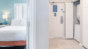 A hotel room with a bed, a nightstand, a lamp, and a window with blinds.