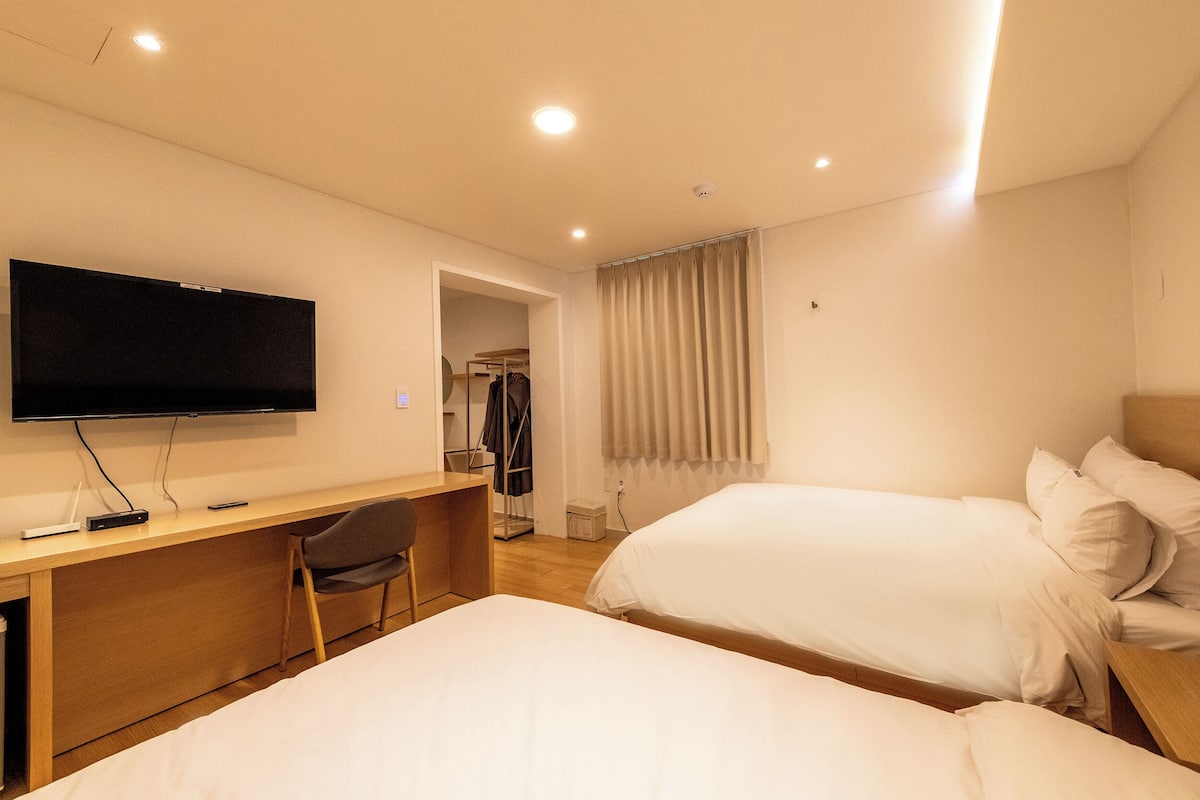 Una camera d'albergo con un letto, una scrivania con una sedia, una televisione e un armadio.