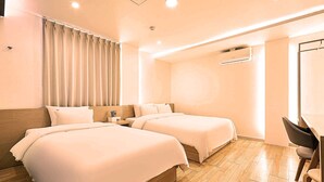 Quarto de hotel com duas camas, uma mesa e um ar condicionado.