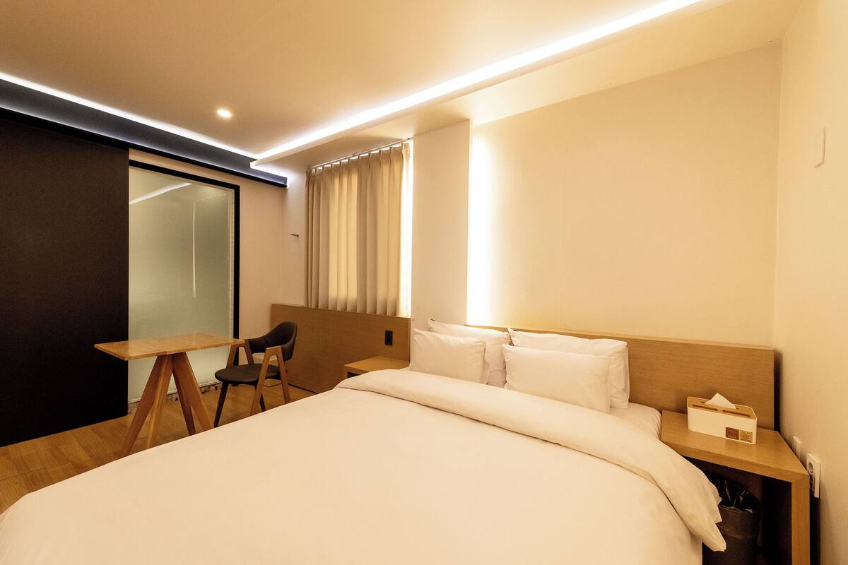 Una camera d'albergo con un letto, una scrivania, una sedia e un comodino.