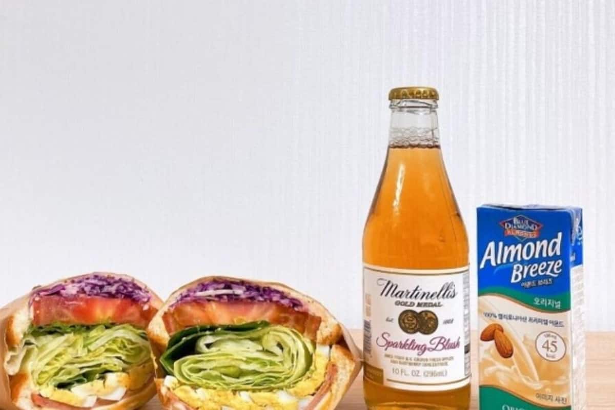 Un panino, una bottiglia di Martinelli's Sparkling Blush e una confezione di Almond Breeze.