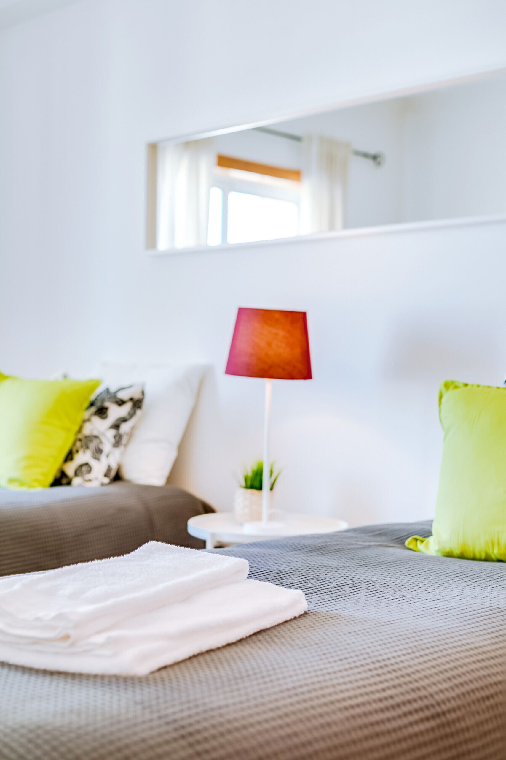 A neatly arranged bedroom with a bed, pillows, a lamp, and a small table.
