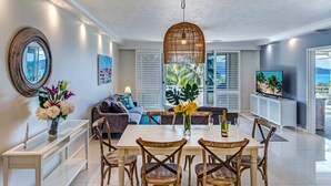 Un espace repas moderne avec une table à plateau en verre, des chaises en bois et un luminaire suspendu au centre.