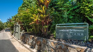 Une enseigne indiquant l’emplacement de Poinciana Lodge, avec un mur en pierre et une végétation luxuriante.